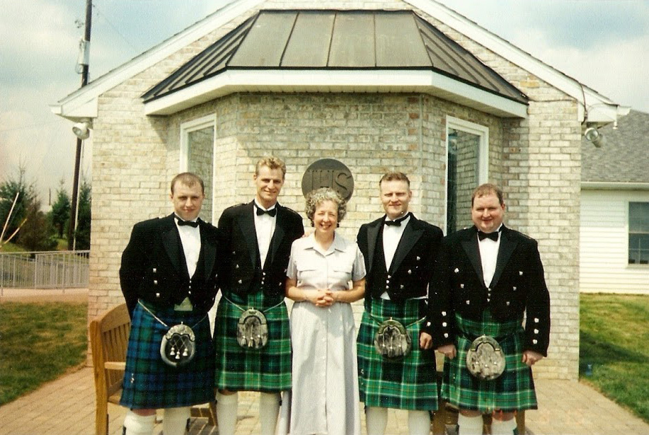 Men in kilts standing in front of a chapel